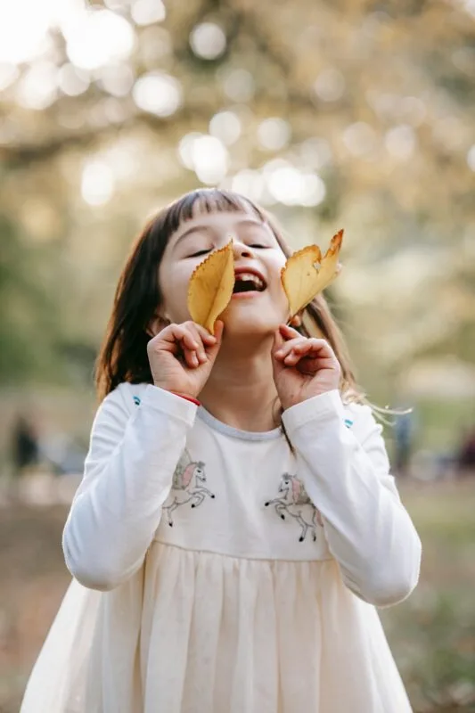 Uma menina segurando folhas ilustrando brincadeiras sensoriais ao ar Livre