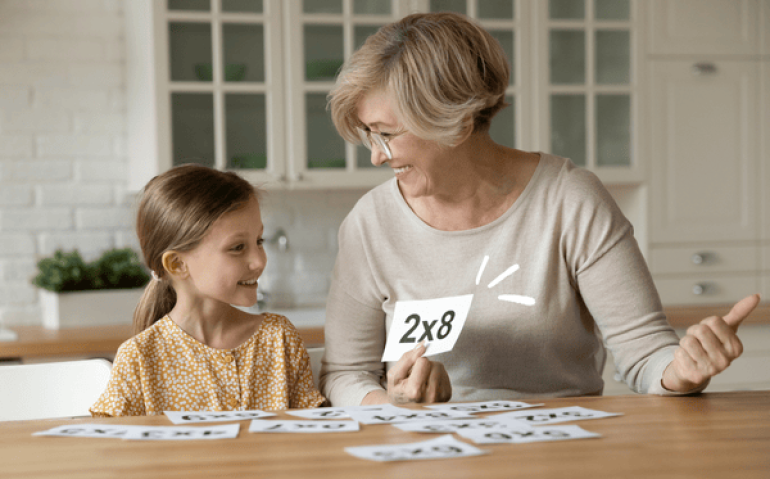 Avó ensinando tabuada a neta usando cartões de multiplicação – ordem correta para ensinar multiplicação.